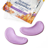 Zwei glitzernde, lila Hydrogel-Augenpads vor der Mystic Pumpkin Verpackung mit Kürbis- und Feigen-Motiv.