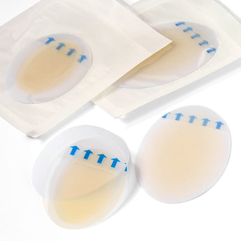 Transparente, ovale Balea Hydrokolloid-Blasenpflaster für die Ferse mit blauen Pfeilmarkierungen auf weißem Hintergrund.