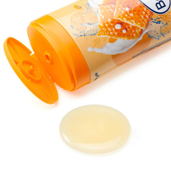 Balea Cremedusche Milch & Honig 300ml Flasche mit geöffnetem Deckel und einem Klecks cremiger Duschgel-Textur auf weißem Grund.