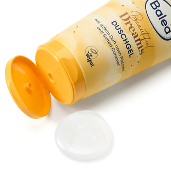 Gelbe Balea Beautiful Dreams Duschgel-Tube mit geöffnetem Deckel und einem Klecks transparentem Duschgel auf weißem Grund.