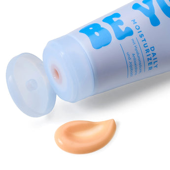 Hellblaue Balea Be You Daily Moisturizer Tube mit geöffnetem Deckel und einem Klecks pfirsichfarbener Gesichtscreme.