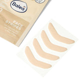 Vier hautfarbene, elastische Balea Face Stripes Lifting-Patches auf einer Trägerfolie neben der beigen Produktverpackung.
