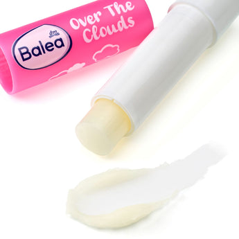 Balea Over the Clouds Lippenpflegestift in Pink mit weißer Kappe und einem cremigen Lippenbalsam-Abstrich auf weißem Grund.