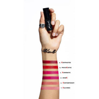 Hand hält schwarzen Karl Lagerfeld Lippenstift mit sechs verschiedenen Rosé- bis Rottönen als Farbmuster auf dem Unterarm.