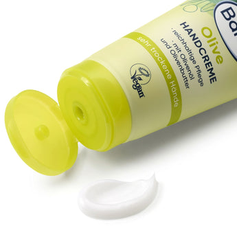 Balea Handcreme Olive in hellgrüner Tube mit offenem Klappdeckel und einem Klecks weißer Creme auf weißem Hintergrund.